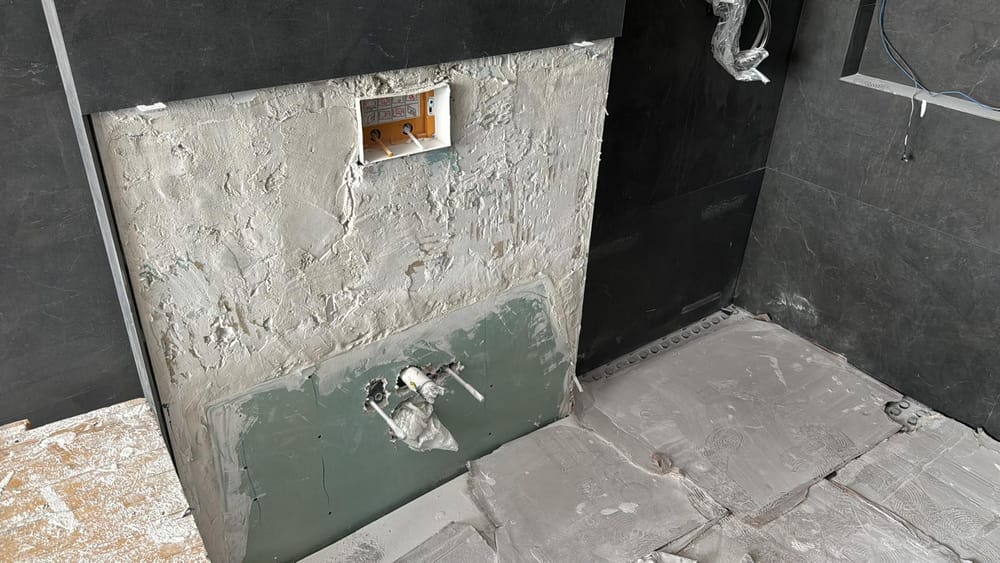 Paramento del baño rehecho, con la fontanería al descubierto